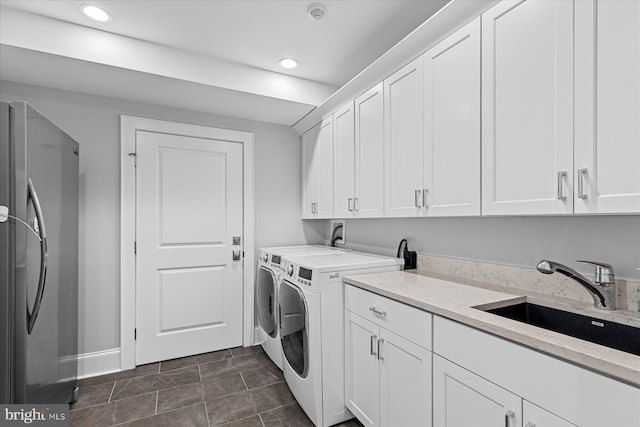 clothes washing area with sink, dark tile floors, cabinets, and washing machine and clothes dryer