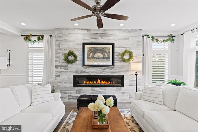 living room featuring crown molding, hardwood / wood-style flooring, a tile fireplace, tile walls, and ceiling fan