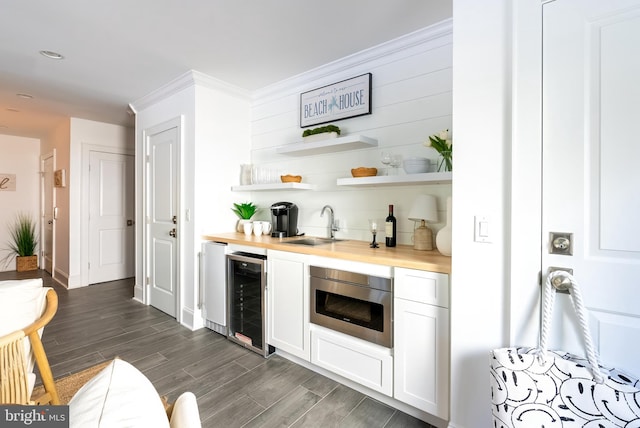 bar with wine cooler, stainless steel oven, dark hardwood / wood-style flooring, sink, and white cabinetry