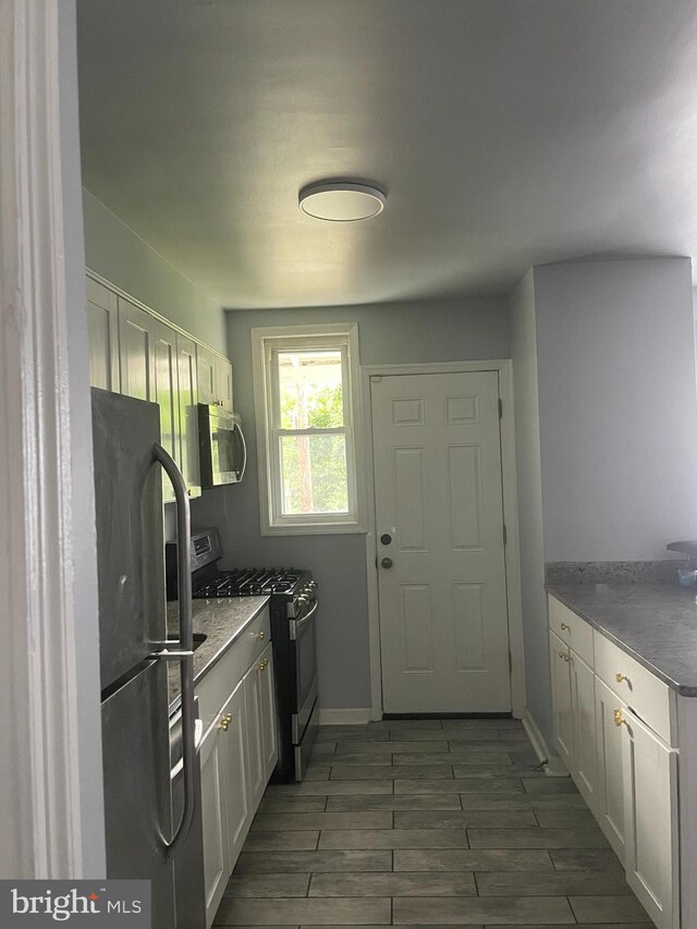 kitchen with dark stone countertops, appliances with stainless steel finishes, and white cabinets