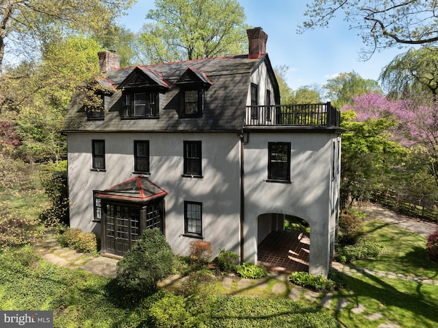 back of house with a balcony and a lawn