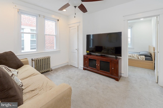 living room featuring ceiling fan, carpet flooring, radiator heating unit, and a wealth of natural light