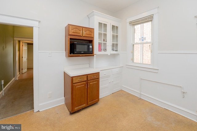 kitchen with white cabinets, black microwave, and light carpet