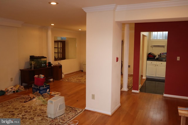 hall featuring decorative columns, ornamental molding, and wood-type flooring