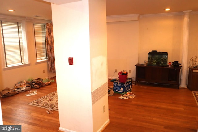 hallway with crown molding, hardwood / wood-style floors, and ornate columns