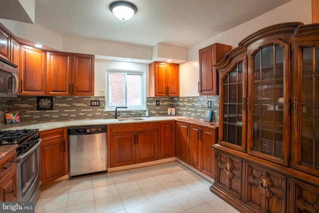 kitchen featuring light stone countertops, appliances with stainless steel finishes, backsplash, light tile flooring, and sink