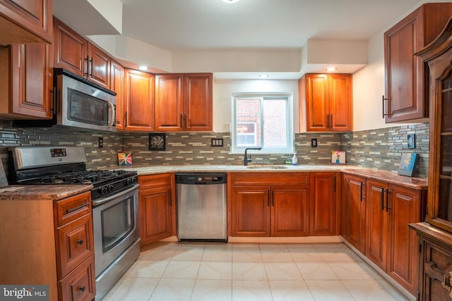 kitchen featuring light tile flooring, appliances with stainless steel finishes, tasteful backsplash, and light stone counters