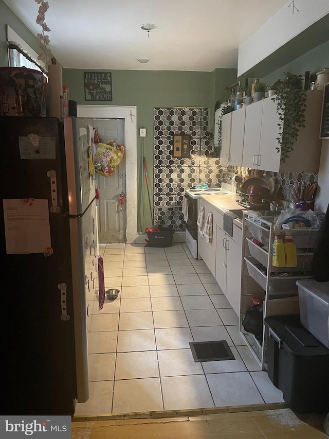 kitchen with refrigerator, white cabinets, and light tile floors