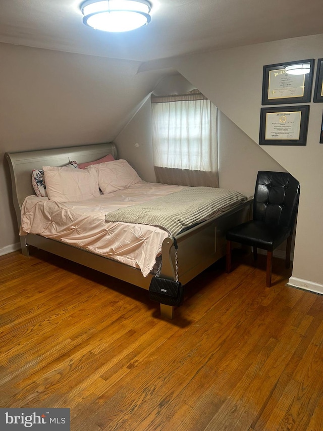 bedroom with wood-type flooring and vaulted ceiling