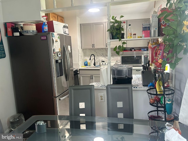 kitchen with backsplash, sink, stainless steel appliances, and light stone counters