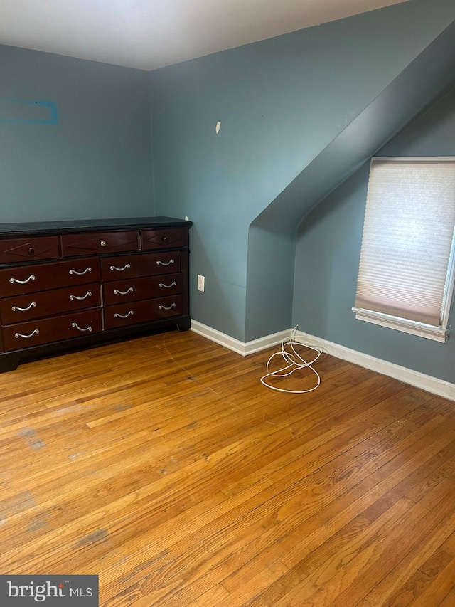 unfurnished bedroom featuring lofted ceiling and light wood-type flooring