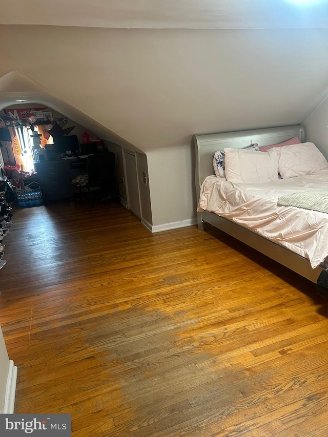 unfurnished bedroom with wood-type flooring and vaulted ceiling