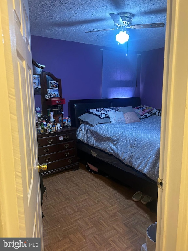 bedroom featuring parquet flooring, ceiling fan, and a textured ceiling