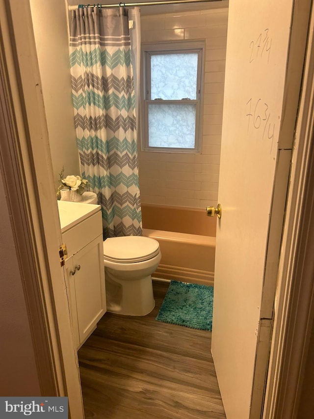 full bathroom featuring wood-type flooring, shower / tub combo, vanity, and toilet