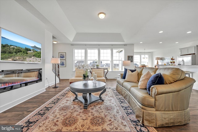 living room featuring hardwood / wood-style flooring, an inviting chandelier, and a tray ceiling