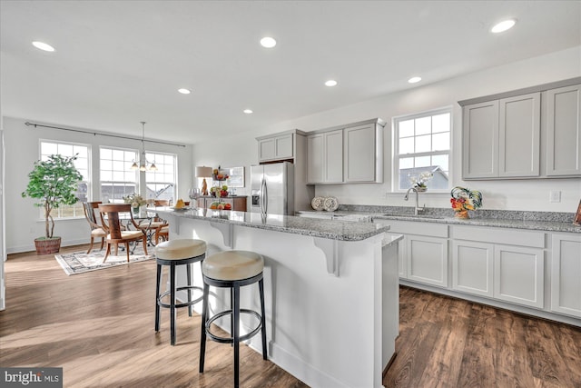 kitchen with dark hardwood / wood-style flooring, stainless steel fridge, a center island, and sink