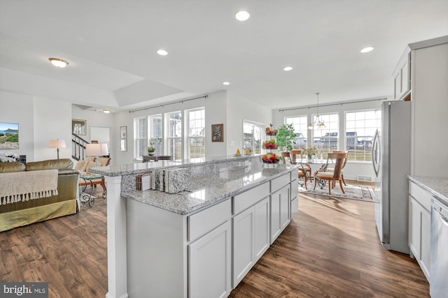 kitchen featuring a center island, dark wood-type flooring, hanging light fixtures, stainless steel fridge, and white cabinetry