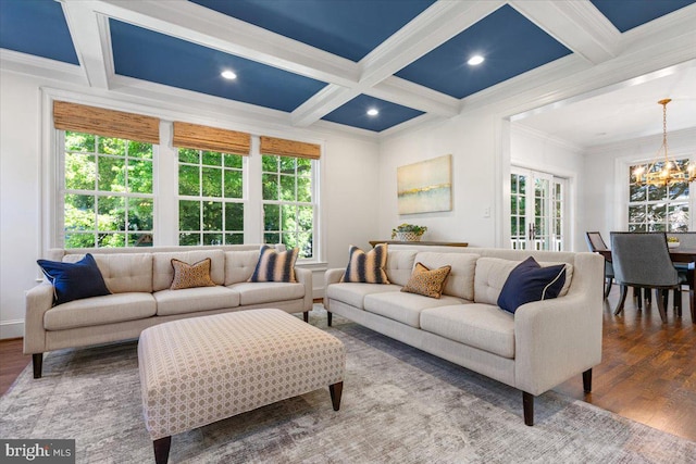 living room featuring a wealth of natural light, coffered ceiling, an inviting chandelier, and hardwood / wood-style floors