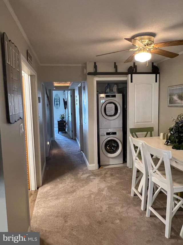 interior space with carpet floors, a barn door, and stacked washing maching and dryer