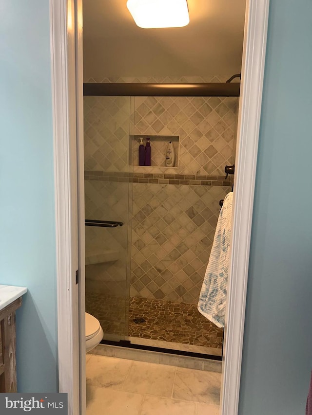 bathroom with an enclosed shower, vanity, tile floors, and toilet