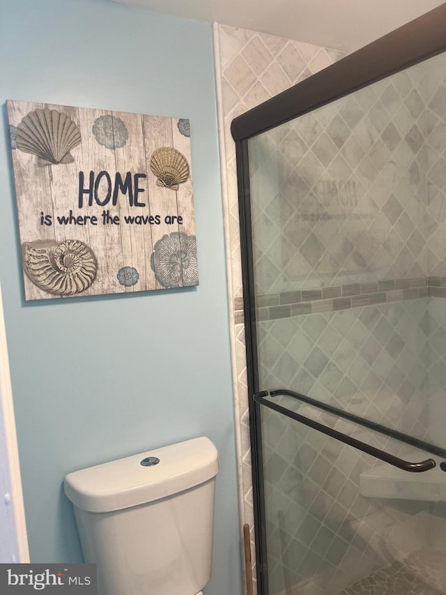 bathroom with a shower with door and toilet