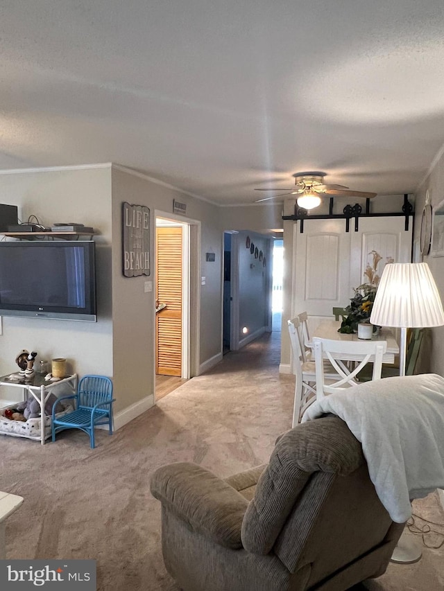 living room with ornamental molding, carpet, ceiling fan, and a barn door