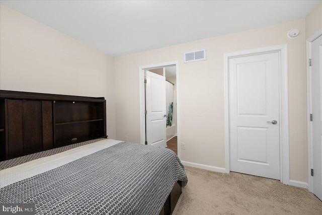 bedroom with light carpet and connected bathroom