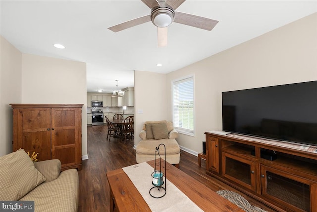 living room featuring ceiling fan with notable chandelier and dark hardwood / wood-style flooring