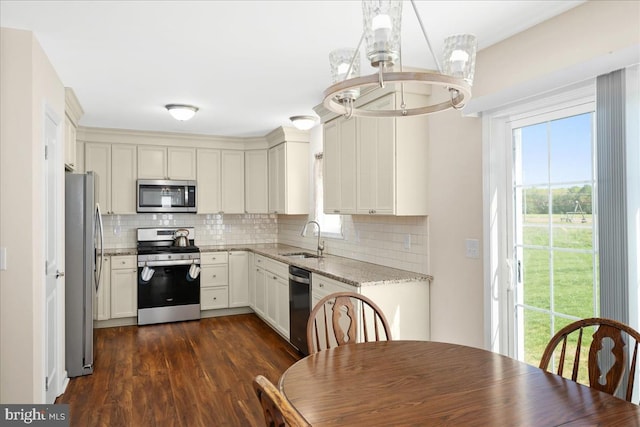 kitchen featuring stainless steel appliances, tasteful backsplash, light stone counters, sink, and dark hardwood / wood-style flooring