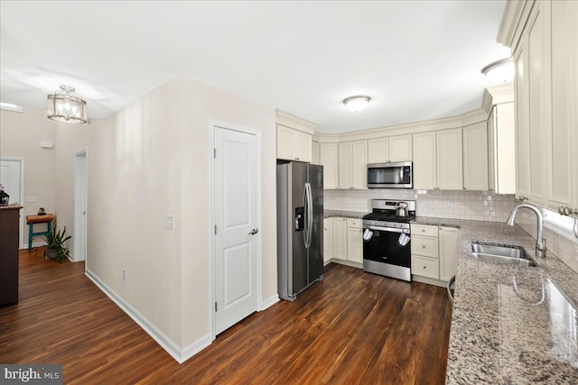 kitchen featuring light stone countertops, appliances with stainless steel finishes, backsplash, dark hardwood / wood-style floors, and sink