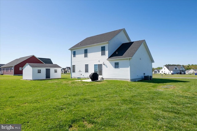 rear view of property with central AC unit, an outdoor structure, and a lawn