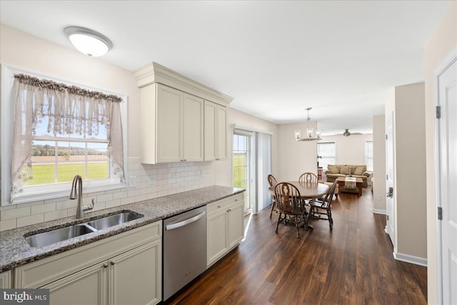 kitchen with light stone counters, sink, dark wood-type flooring, and stainless steel dishwasher