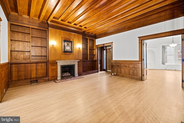 unfurnished living room featuring built in features, light hardwood / wood-style floors, wood walls, and wood ceiling