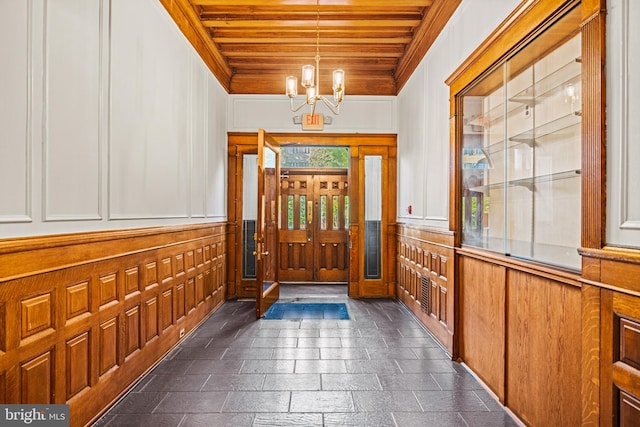 entrance foyer with wooden ceiling, dark tile flooring, and an inviting chandelier