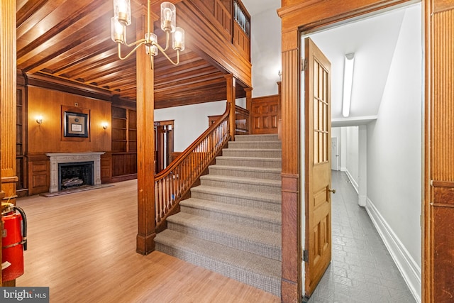 stairs featuring beam ceiling, a chandelier, wood walls, hardwood / wood-style flooring, and wooden ceiling