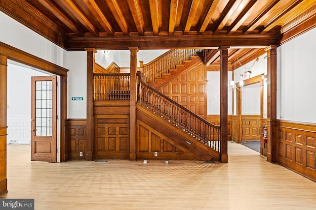 entryway featuring beamed ceiling, light hardwood / wood-style floors, crown molding, and ornate columns