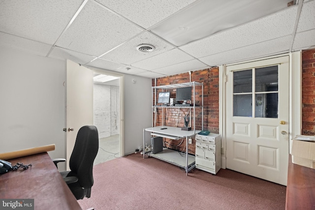 office with carpet floors, a paneled ceiling, and brick wall