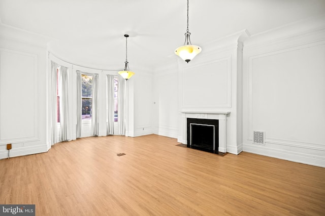 unfurnished living room featuring crown molding, a high end fireplace, and light hardwood / wood-style flooring