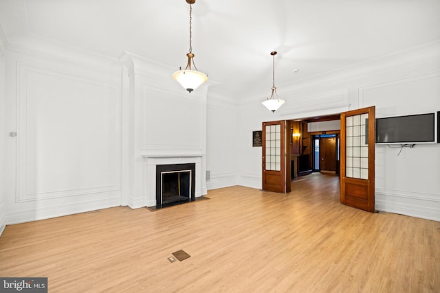 unfurnished living room with light hardwood / wood-style flooring, crown molding, and french doors