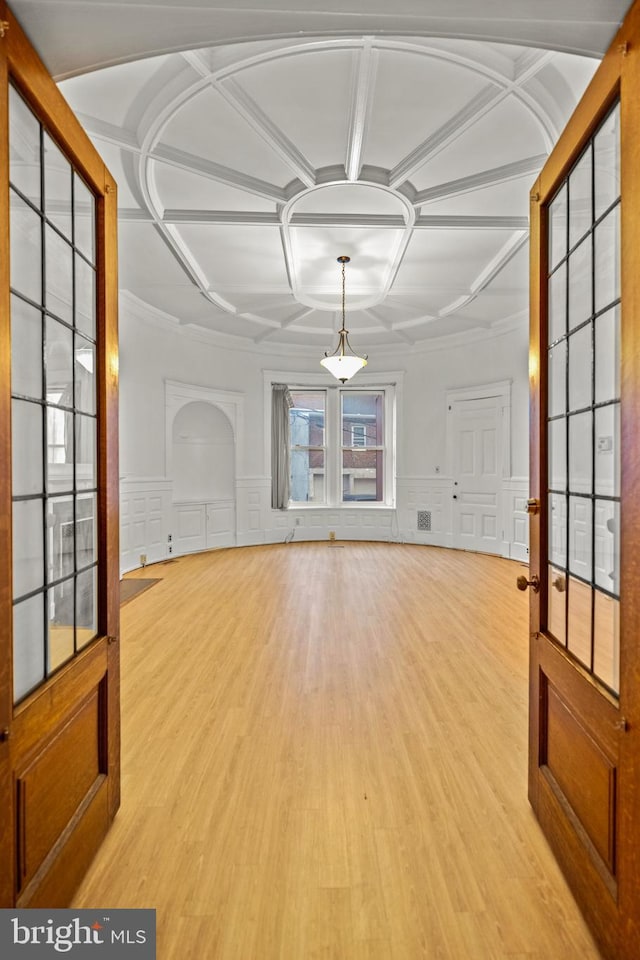 unfurnished living room with coffered ceiling and light wood-type flooring