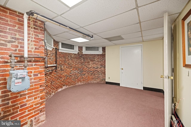 basement with brick wall and a drop ceiling