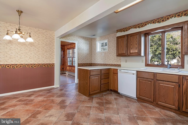 kitchen featuring sink, white dishwasher, hanging light fixtures, and a notable chandelier