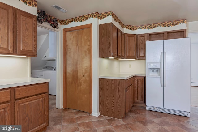 kitchen with a baseboard heating unit, white fridge with ice dispenser, and washing machine and clothes dryer