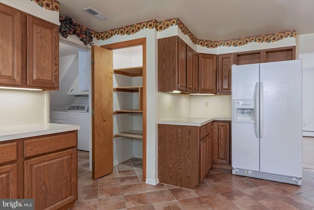 kitchen featuring separate washer and dryer, white fridge with ice dispenser, and a baseboard heating unit