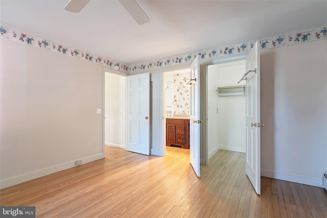 unfurnished bedroom featuring connected bathroom, ceiling fan, light hardwood / wood-style floors, a walk in closet, and a closet