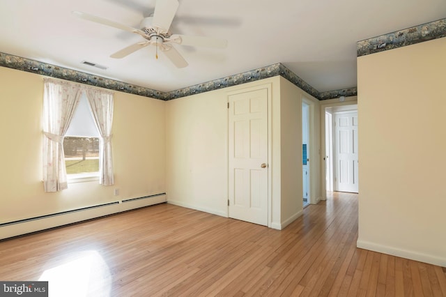 spare room featuring ceiling fan, light hardwood / wood-style flooring, and a baseboard heating unit