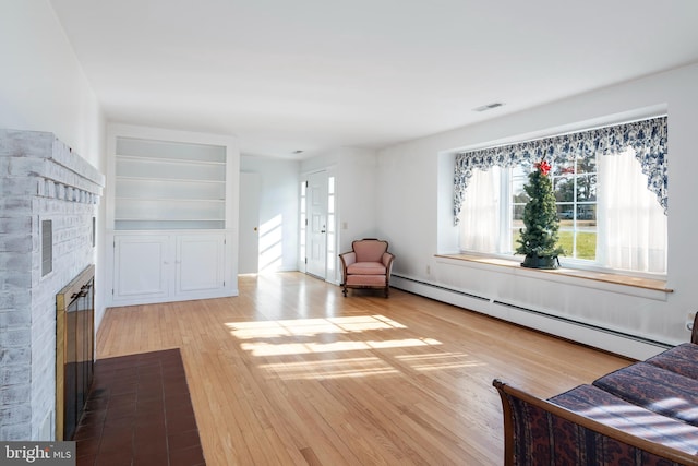 unfurnished living room featuring baseboard heating and light hardwood / wood-style flooring