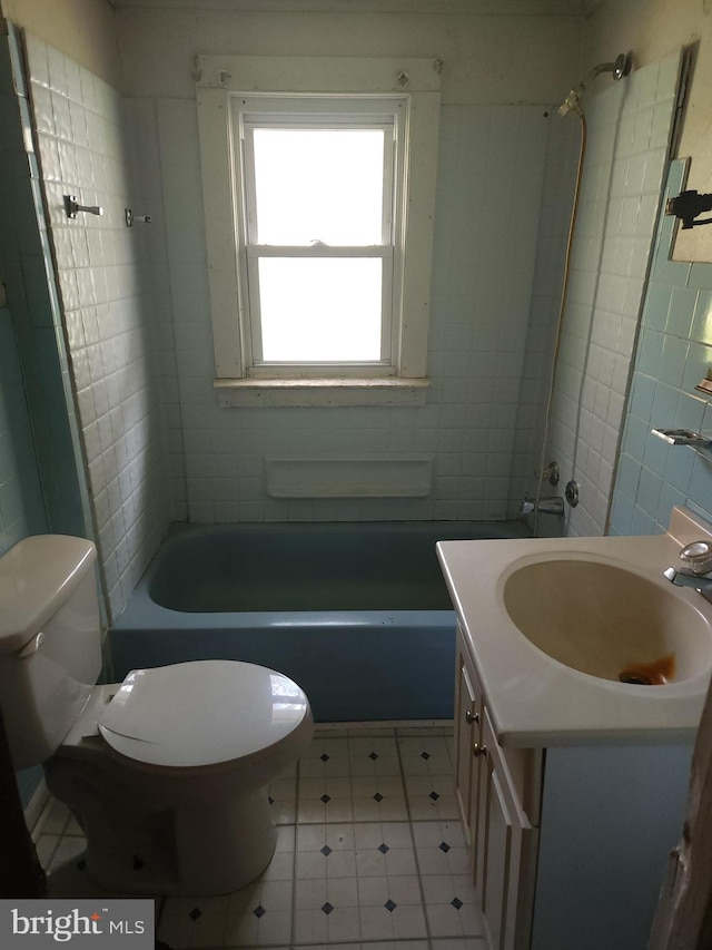 full bathroom with tile flooring, tiled shower / bath, vanity, and toilet