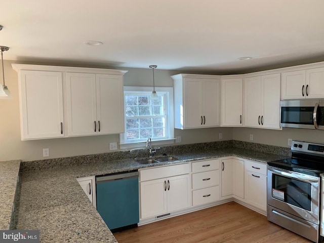 kitchen featuring appliances with stainless steel finishes, sink, pendant lighting, and white cabinets