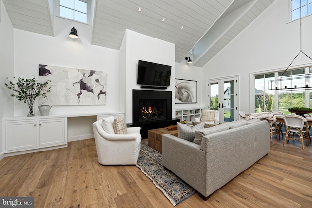 living room with light hardwood / wood-style flooring, high vaulted ceiling, and french doors